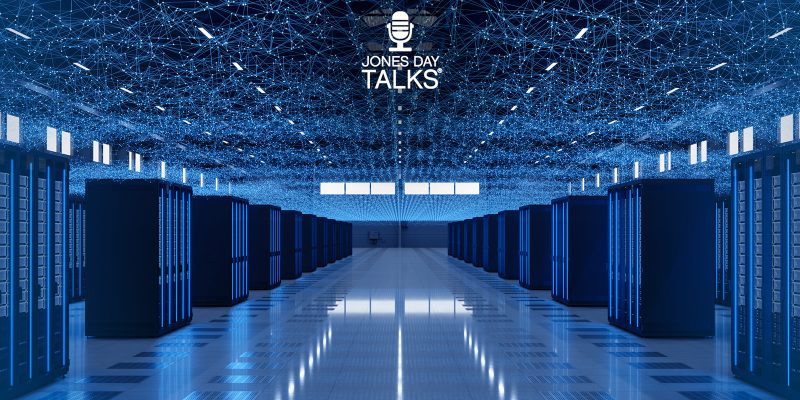 Interior of a futuristic data center with rows of blue-lit server racks and a digital network grid on the ceiling, representing the concept of data centers as the fourth utility – featured on Jones Day Talks.